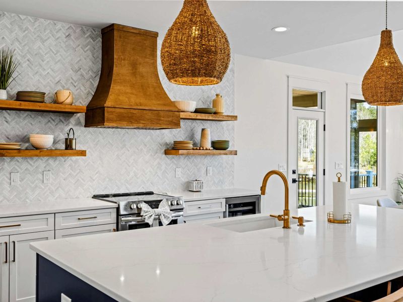 Kitchen Details - A statement wood hood, open shelving, and a stainless range with brushed-gold fixtures bring warmth to the gourmet kitchen.