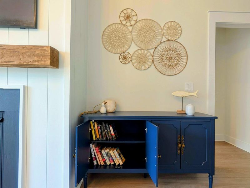 Reading Corner - A navy sideboard stocked with books and coastal touches adds a quiet, characterful corner to the lake-view great room.