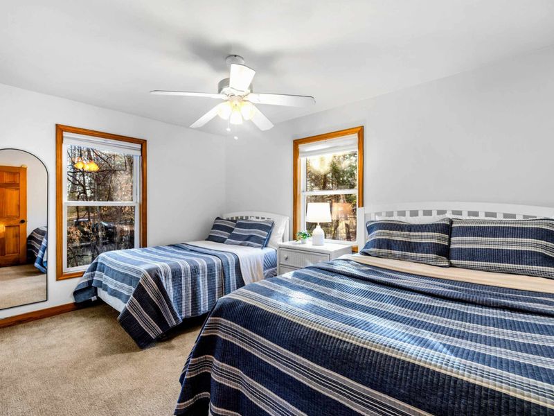 Bright and Airy Retreat – This inviting bedroom features two cozy beds, large windows for natural light, and a ceiling fan to keep you cool after sunny lake days.