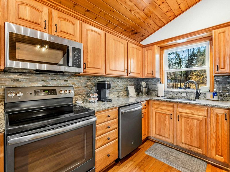 Modern Kitchen Detail - Focus on culinary excellence in this kitchen equipped with stainless steel appliances, stylish backsplash, and ample counter space for meal prep, set against a backdrop of natural wood aesthetics.