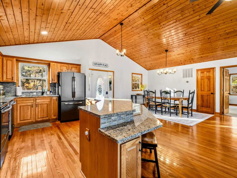 Integrated Dining and Kitchen Space - This open-plan area blends a spacious kitchen with sleek wooden cabinetry and granite countertops seamlessly into a dining area, perfect for social meals and family gatherings.
