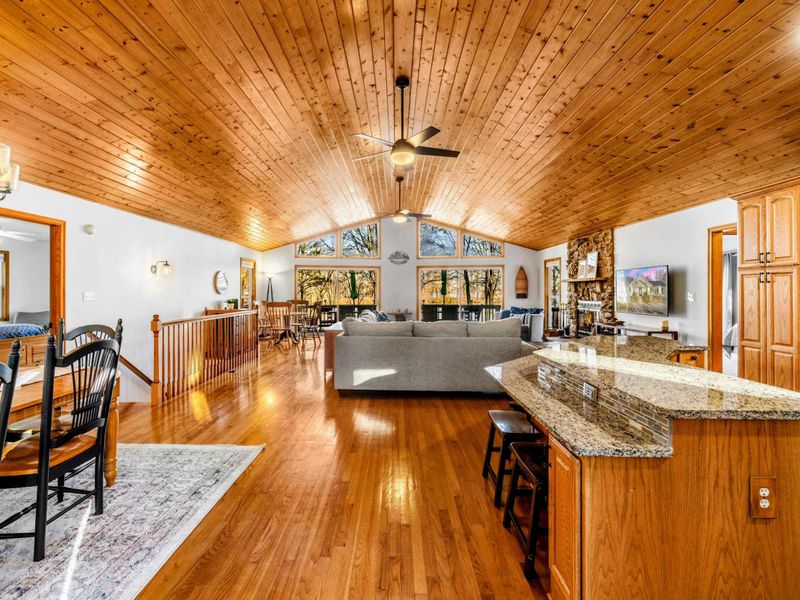 Expansive Open-Plan Living – This grand room features a high, vaulted wooden ceiling that enhances its spacious layout, encompassing a modern kitchen with a central island, a cozy living area, and a formal dining space, perfect for hosting and everyd