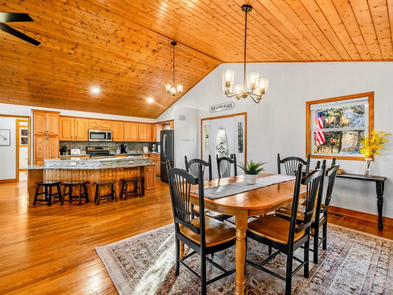 Open Dining and Kitchen Space – Enjoy meals at this elegant wooden table under vaulted wooden ceilings, conveniently adjacent to a spacious kitchen with a bar counter. Perfect for seamless dining and entertaining.