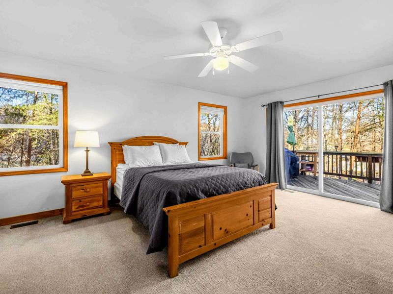 Spacious Primary Suite – Unwind in this inviting lakeside bedroom featuring a plush bed, ample natural light, and sliding doors that open directly to the deck for peaceful morning views.