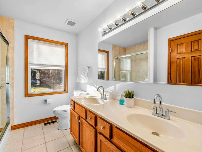 Bright En-Suite Bathroom – The en-suite bath is equipped with a double vanity, large mirror, and natural light—offering a cheerful and functional space to begin and end your day.