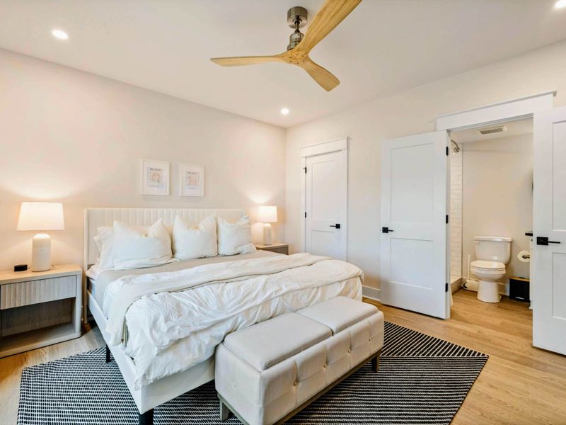 Bedroom 4 - King bed with plush white bedding, tufted ottomans at the foot, and direct access to the en-suite bath.