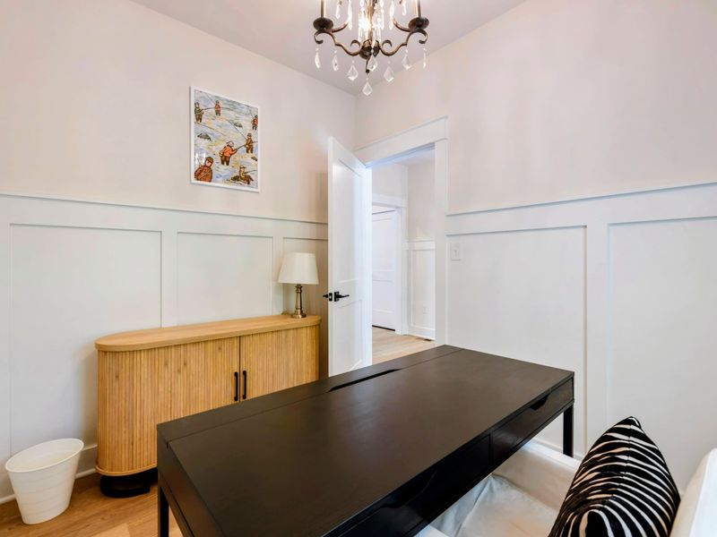 Office - Natural wood credenza and a chandelier complement the refined workspace with board-and-batten walls.