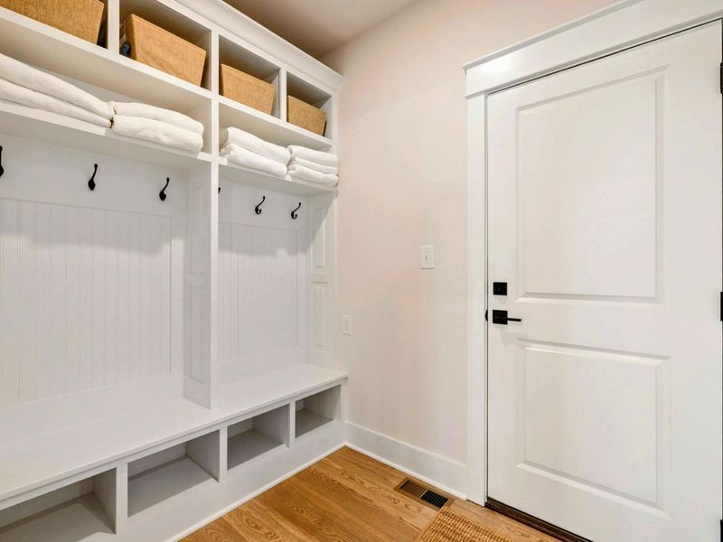 Mudroom - Built-in white cubbies with hooks, bench seating, and woven baskets keep the entryway organized.