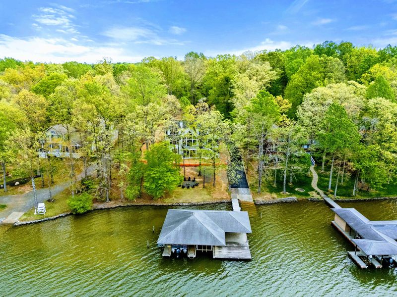 Aerial - The home, dock, and covered boathouse seen from above alongside neighboring lakefront properties.