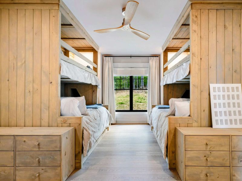 Bunk Room - Custom built-in bunks with natural wood paneling, four beds, built-in drawers, and a window at the end.