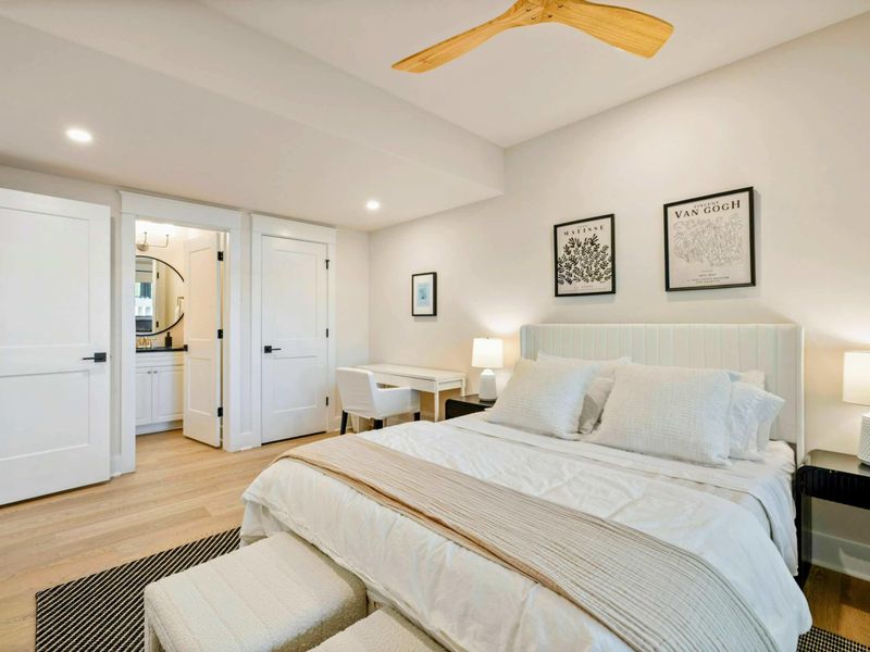 Bedroom 6 - King bed with a channel-tufted headboard, gallery wall art, and a doorway to the en-suite bath.
