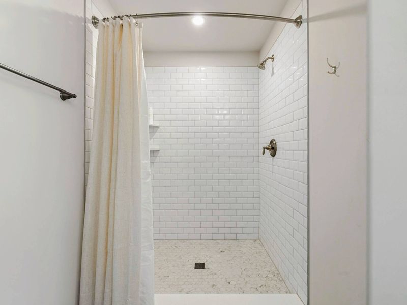 Bathroom - Walk-in shower with crisp white subway tile and built-in corner shelves for toiletries.