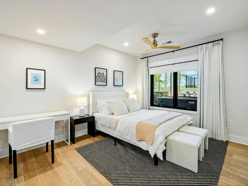 Bedroom 5 - Queen bed with a white desk for remote work and views out to the deck through black-framed windows.