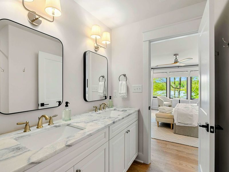 Bathroom - Double vanity with marble countertop, black-framed mirrors, and brass fixtures adjoining the bedroom.