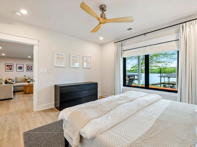 Bedroom 3 - Views of the lake and dock through the large window, with a dark dresser and open doorway to the living area.