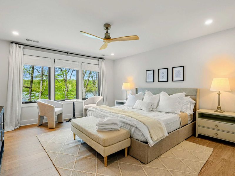 Bedroom 2 - King bed with white bedding and a sitting area with two cream barrel chairs overlooking the lake.