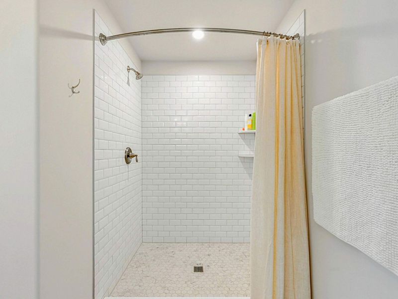 Bathroom - Spacious walk-in shower with white subway tile and mosaic tile flooring.