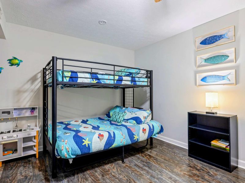 Bunk Room - Alternate angle showing a full-over-full bunk with sea creature quilt, play kitchen, turtle wall art, and fish prints.