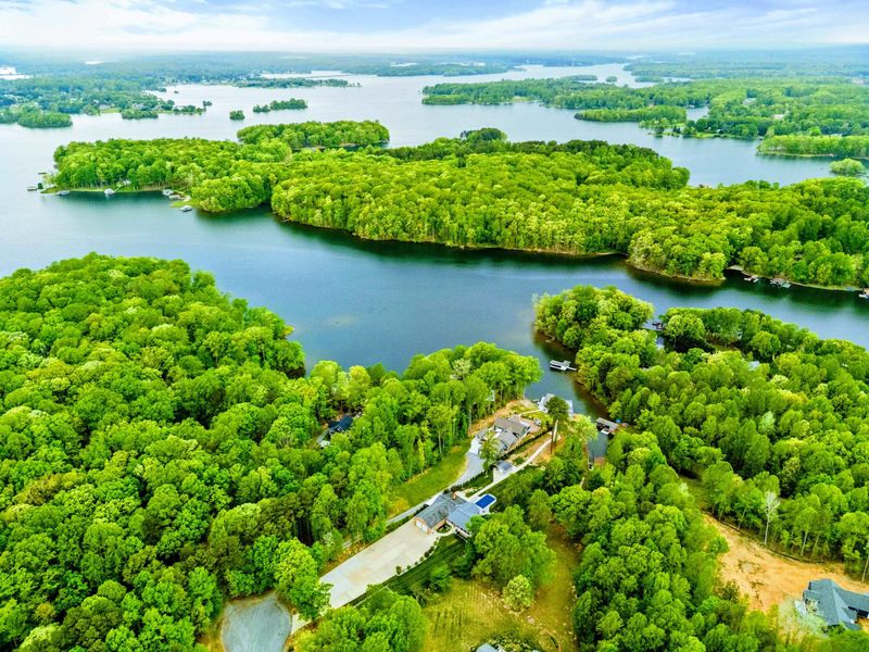 Aerial - Wide drone shot over the Lake Anna peninsula showing the home's wooded waterfront location and open water beyond.