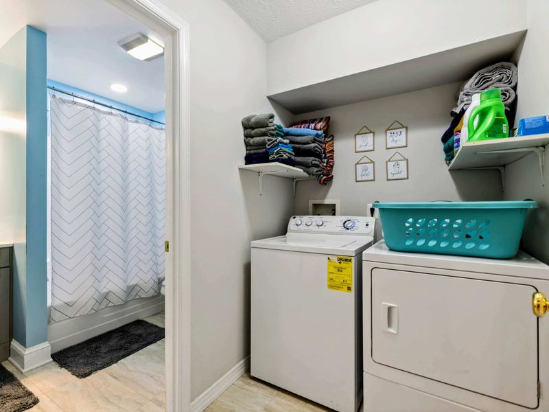 Laundry - Second washer and dryer in a nook adjacent to the blue bathroom, with shelf storage and extra towels.