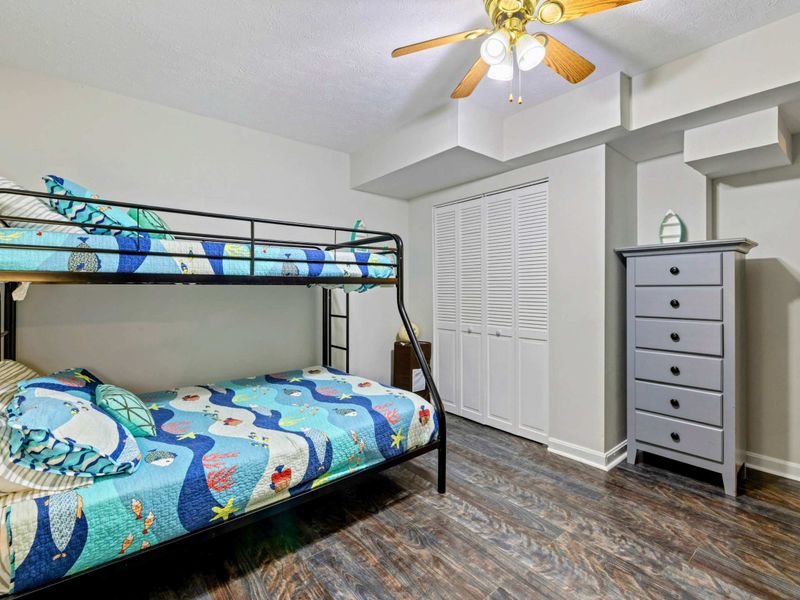 Bunk Room - Twin-over-full black metal bunk with ocean-themed bedding, gray dresser, and louvered closet doors.