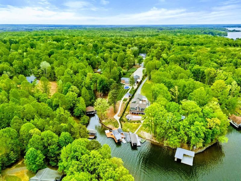 Aerial - Wide drone shot of the cove showing the home's private dock, neighboring properties, and the Virginia forest canopy.