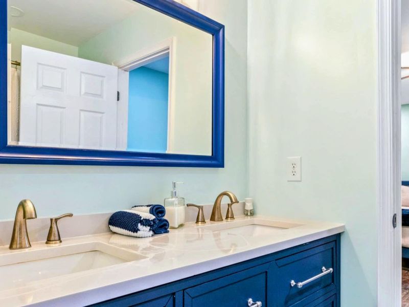 Primary Bathroom - Navy blue double vanity with brass fixtures, matching blue-framed mirror, and mint green walls.