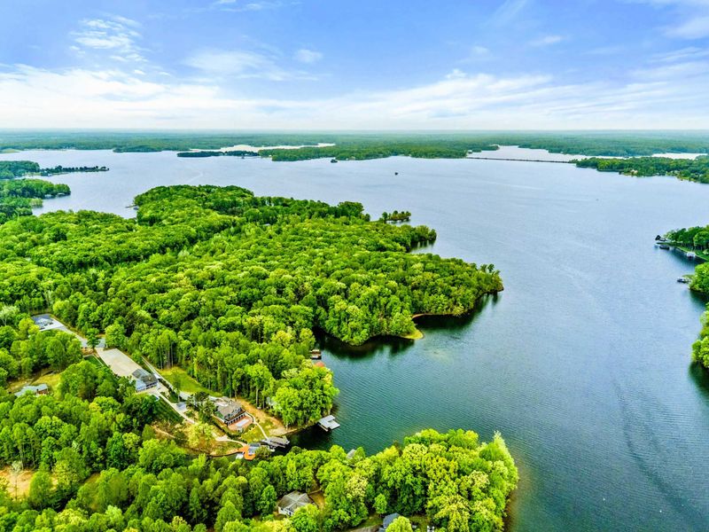 Aerial - Drone view looking across the peninsula and cove with the main lake body sparkling in the distance.