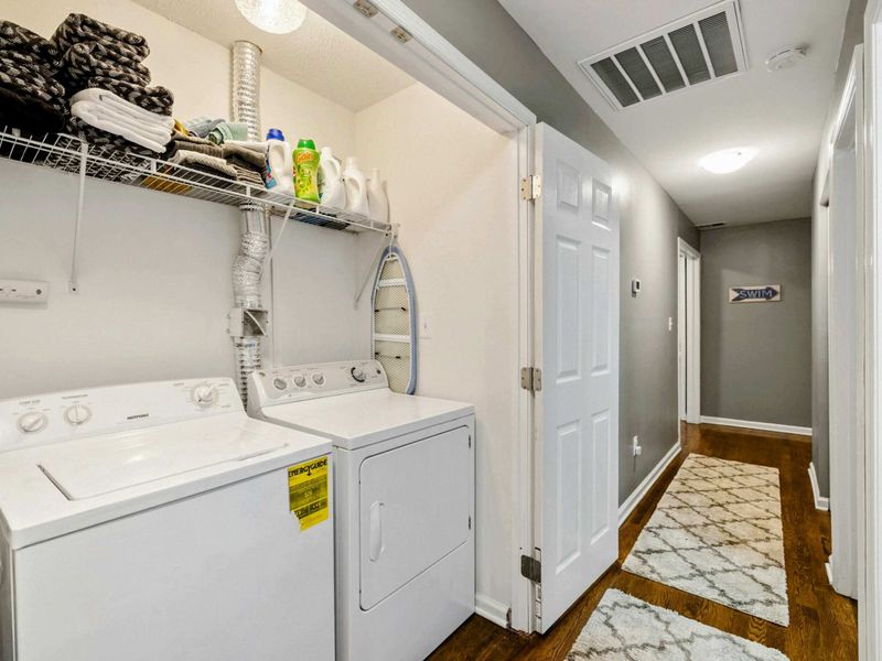Laundry - Full-size washer and dryer in a hallway closet with wire shelving, detergent, and extra towels.