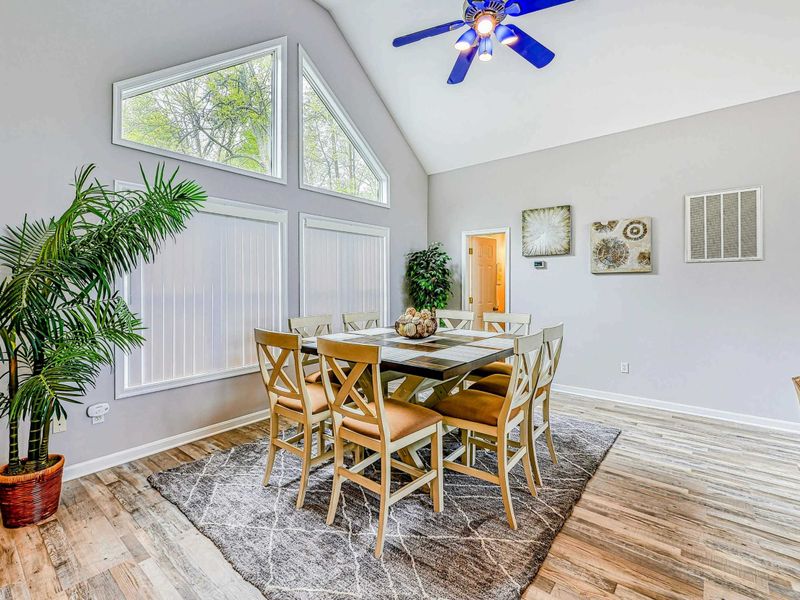 Dining Area - Alternate angle of the farmhouse table with botanical art and palm plant under the vaulted ceiling.