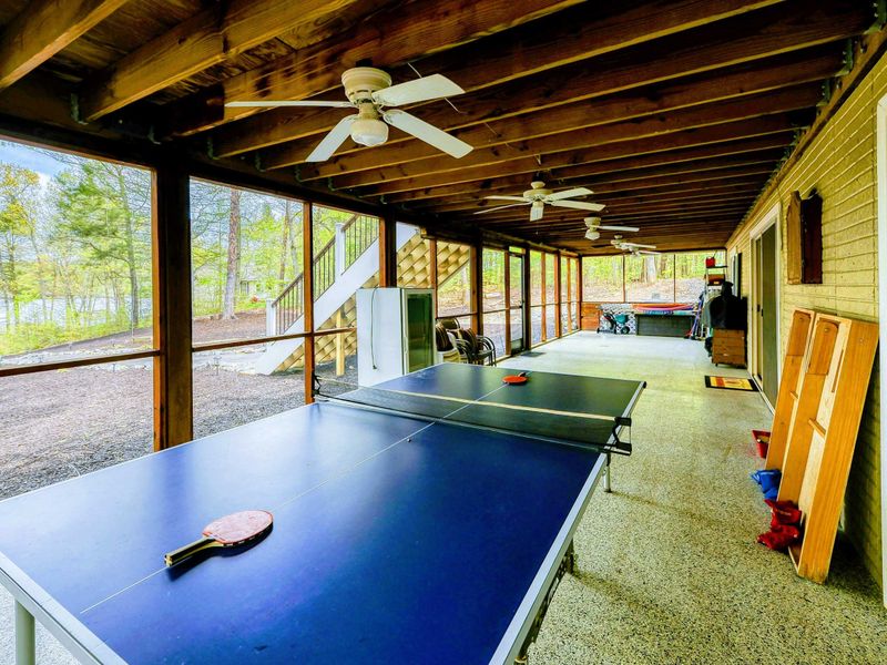 Screened Porch - Ping pong table under exposed beam ceiling with ceiling fans and yard views.