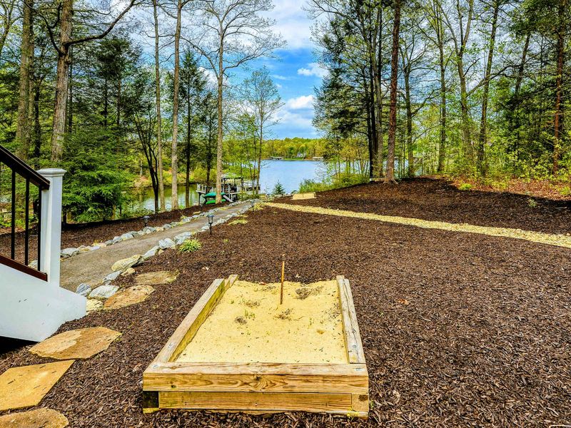Horseshoe Pit - Sand horseshoe pit beside the deck stairs with lake views through the trees.