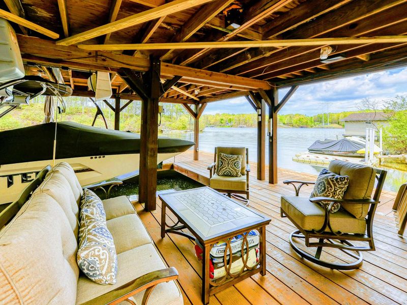 Lower Dock - Boat on the lift under the covered slip with a lounge sofa and open lake views.