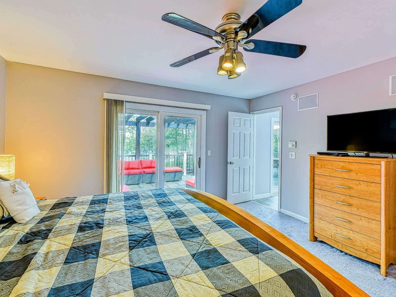 Primary Suite - Alternate showing the TV on the dresser, closet, and sliding doors with the red lounge visible outside.