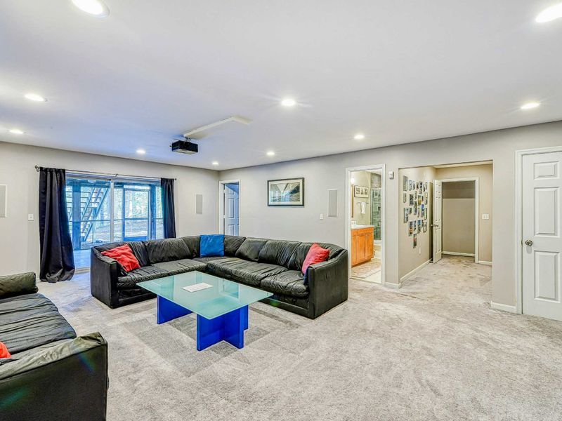 Home Theater - Sectional seating with blue glass coffee table and doorway to the lower level bathroom.
