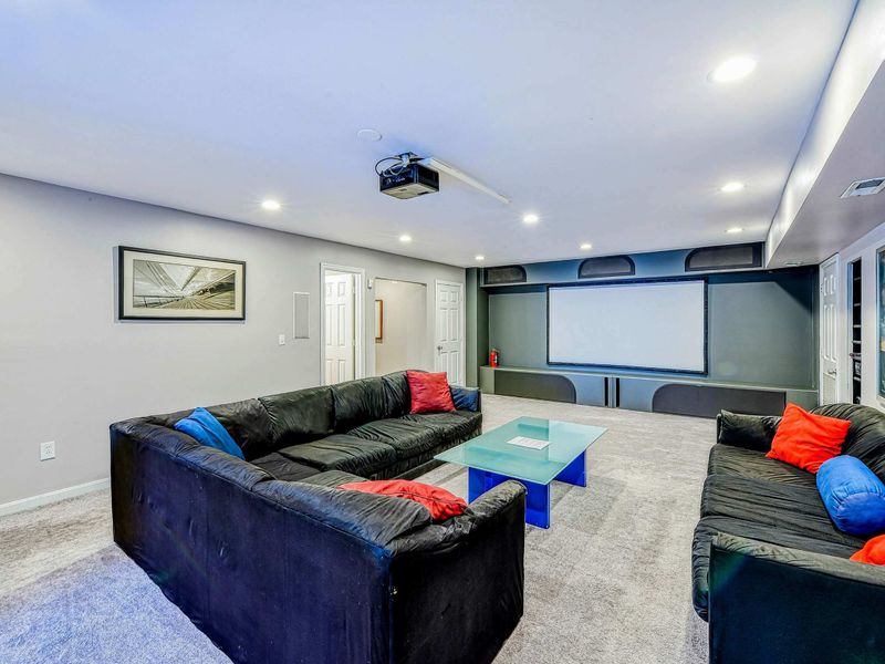 Home Theater - Alternate view showing the projector, screen, dual sectionals, and movie poster collection.