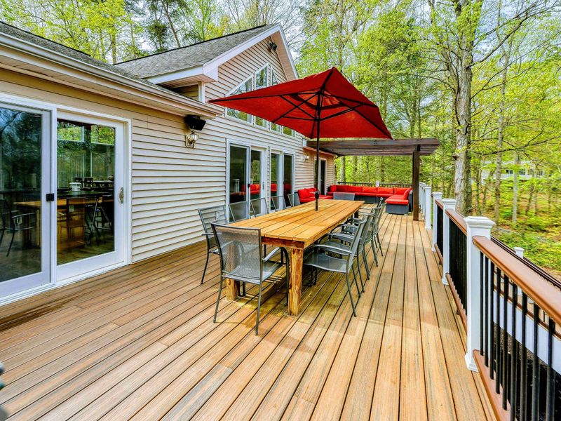 Deck - Wide view of the dining area, red umbrella, pergola seating, and French doors to the living room.