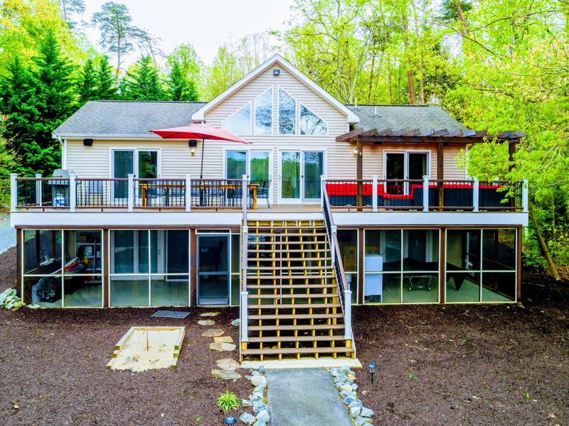 Exterior - Rear of the home showing the A-frame peak, upper deck with red umbrella, and lower screened porch.