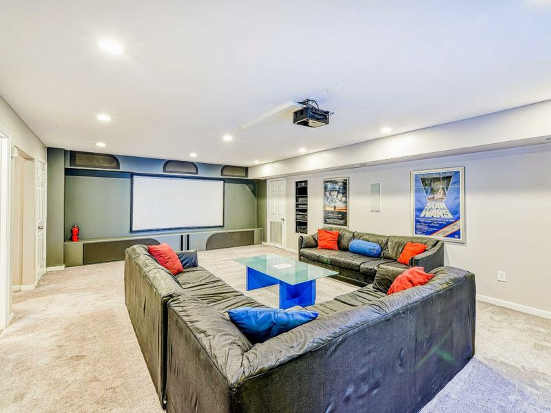 Home Theater - Wide angle of the projection screen, surround sound speakers, and comfortable seating for movie nights.