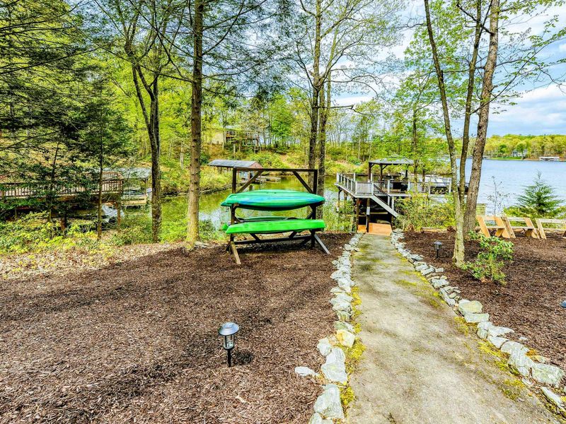 Kayak Storage - Stone-lined walkway to the dock with green kayaks stored on the rack.