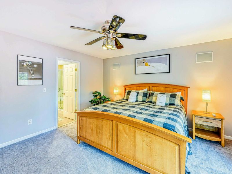 Primary Suite - En suite bathroom entry, maple sleigh bed, and bird artwork in the spacious retreat.