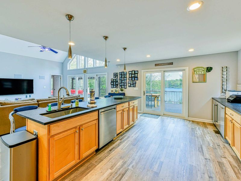 Kitchen - Island sink with pendant lights and sightline through the French doors to the deck and lake.