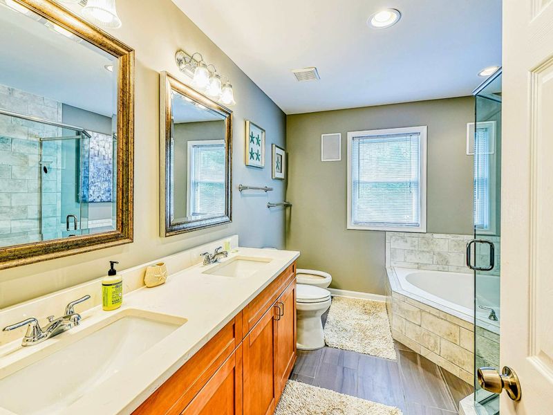 Primary Bathroom - Cherry double vanity with dual sinks, marble soaking tub, glass walk-in shower, and starfish art.