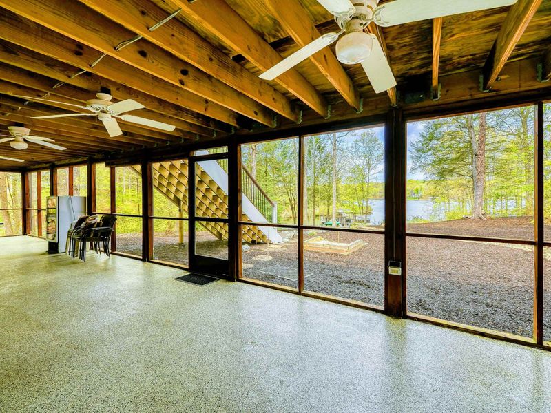 Screened Porch - Spacious screened-in area with ceiling fans and views of the yard and lake through the trees.