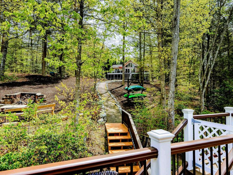 Deck View - Looking down the stairs toward the fire pit, kayak rack, and dock from the upper deck.