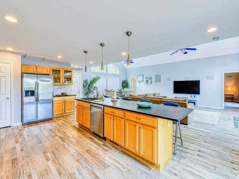 Kitchen - Island with dishwasher and pendant lights open to the vaulted living area beyond.