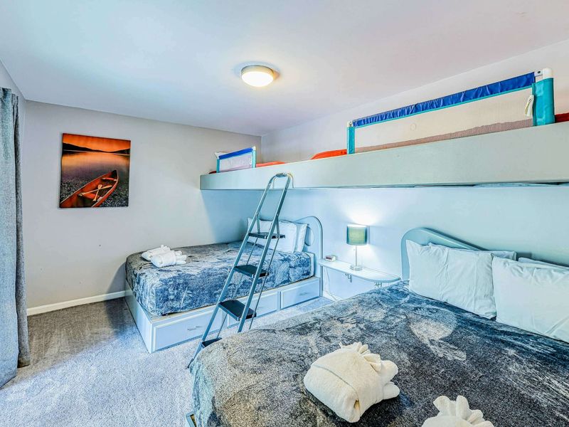 Bunk Room - Custom built-in bunks with ladder, canoe sunset art, and blue-gray bedding on the lower level.