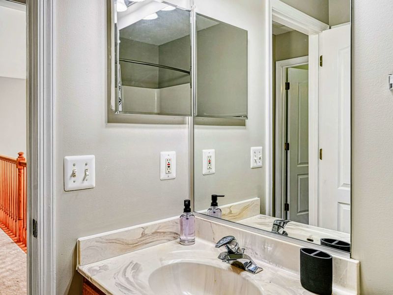 Upper Half Bath - Single marble vanity with mirror at the loft level for convenience.