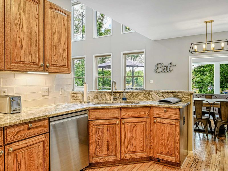 Kitchen - Granite peninsula sink with views through the two-story windows to the living area, dining room, and sunroom.