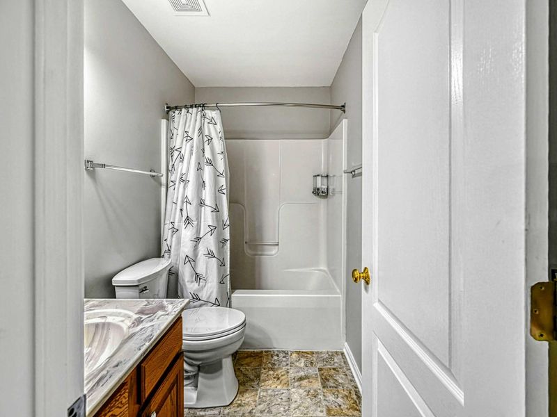Upper Bathroom - Tub and shower combo with patterned curtain, single vanity, and tile floor shared by the upper bedrooms.